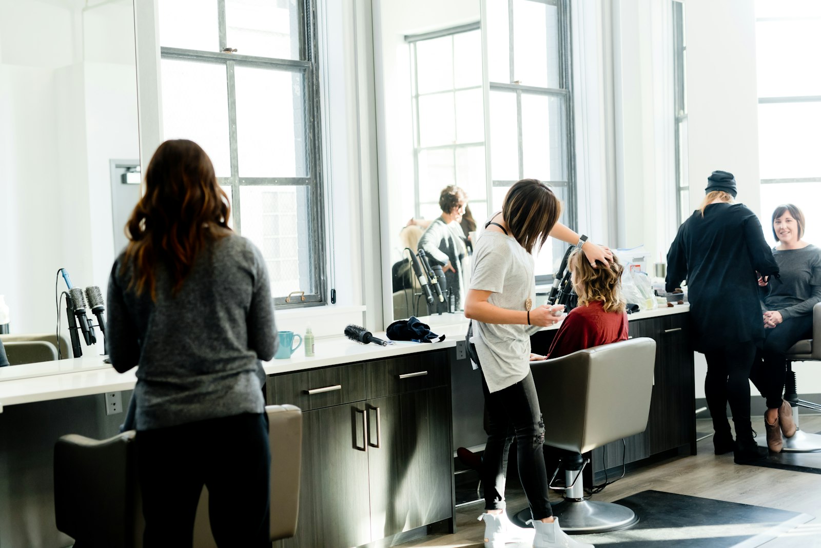 Voller Salon: drei Friseurinnen arbeiten gleichzeitig an Kundinnen